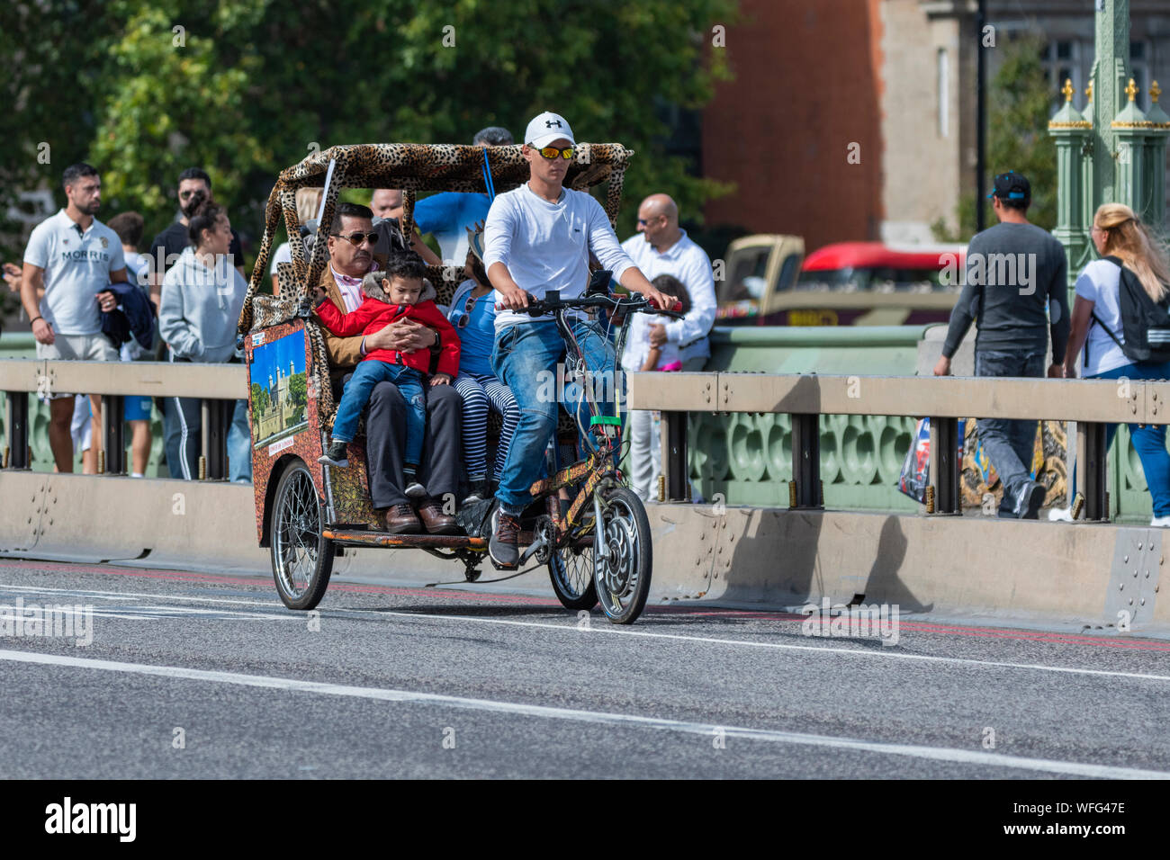 Les touristes comme les passagers sur un trajet touristique dans un pousse-pousse 3 roues ou Pedicab sur Westminster Bridge dans City of London, England, UK. Banque D'Images
