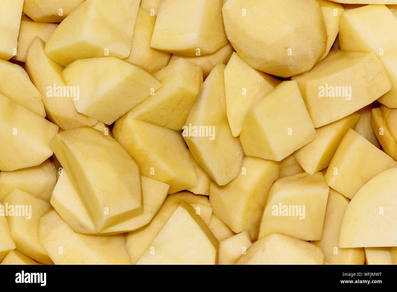 Pommes de terre pelées et coupées en dés dans une passoire en préparation comme ingrédient pour la cuisson d'un repas. Banque D'Images