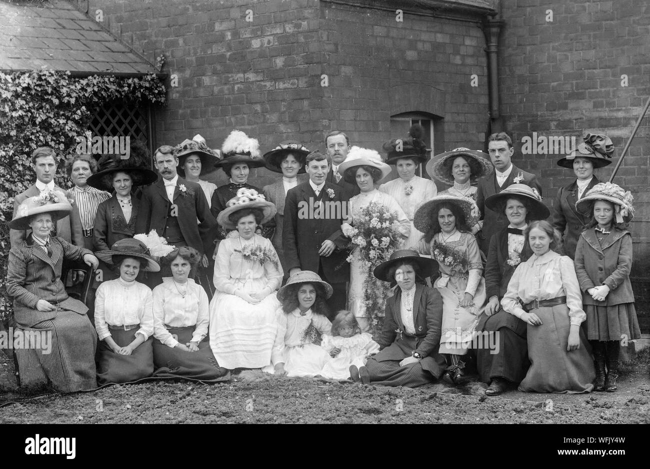 Un vintage style victorien ou au début de l'Edwardian Photographie noir et blanc montrant une fête de mariage qui pose pour la caméra dans un établissement à l'extérieur. La mode très typique de l'époque sur l'affichage. Banque D'Images