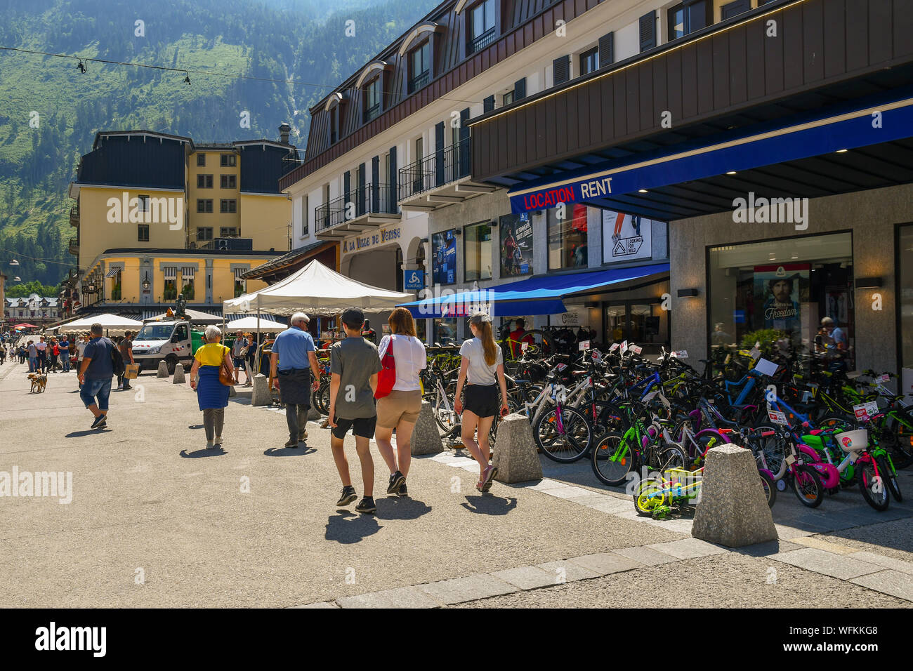 Street View de touristes marchant devant un magasin de bicyclettes avec des vélos pour tous les âges sur le trottoir en une journée d'été, Chamonix-Mont-Blanc, France Banque D'Images