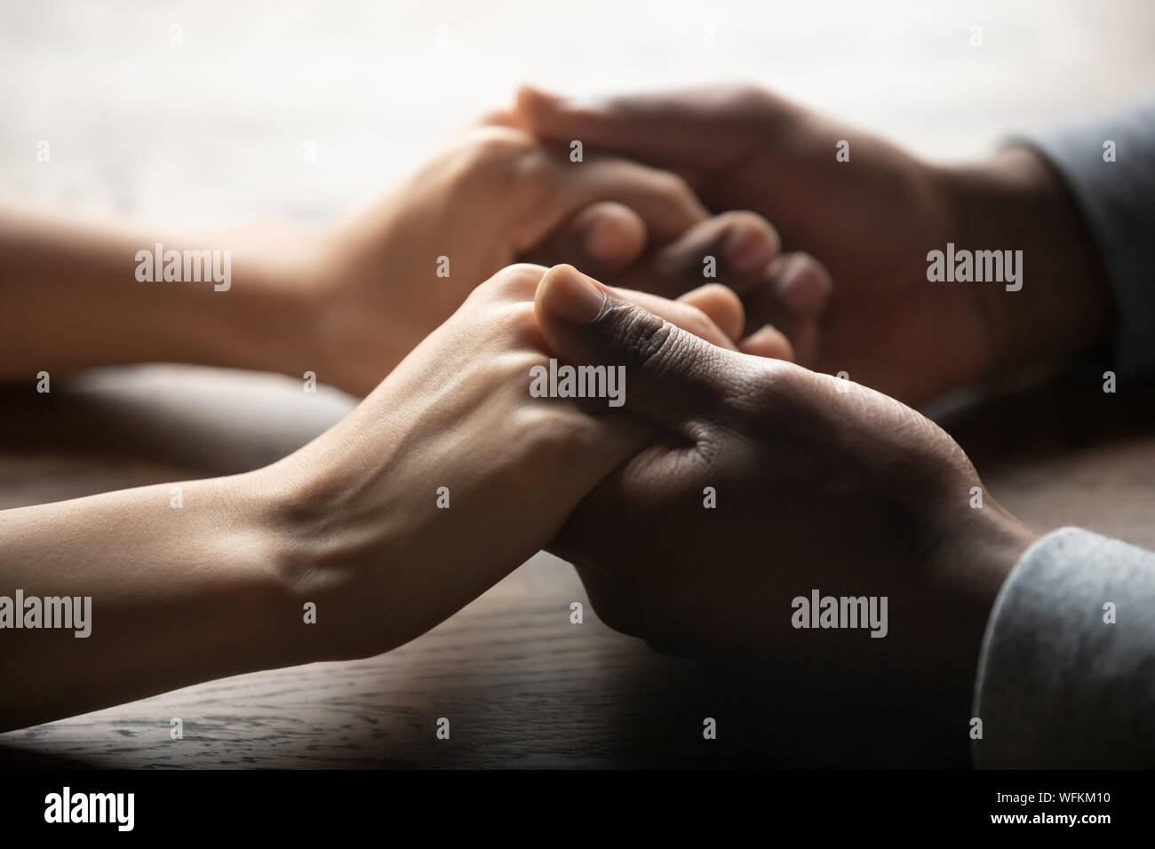 L'origine ethnique mixte couple holding hands on table, Close up view Banque D'Images