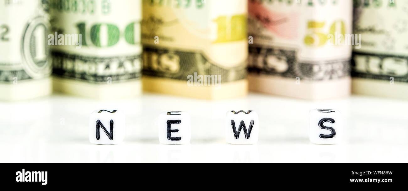 Little White cubes avec des lettres noires de word news sur fond blanc avec des dollars américains dans l'arrière defocused Banque D'Images