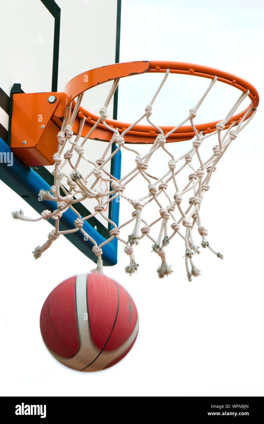 Victoire de basket-ball, une balle en passant par anneau du panier et filet en flou. La réussite d'un point clair en détail, low angle view Banque D'Images