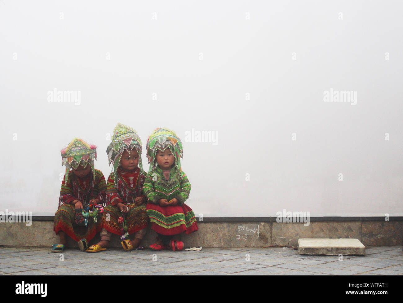 Sapa, Vietnam - 4 juin 2019 - les petites filles dans des vêtements hmong traditionnelle assise sur le bord d'un très soir brumeux Banque D'Images