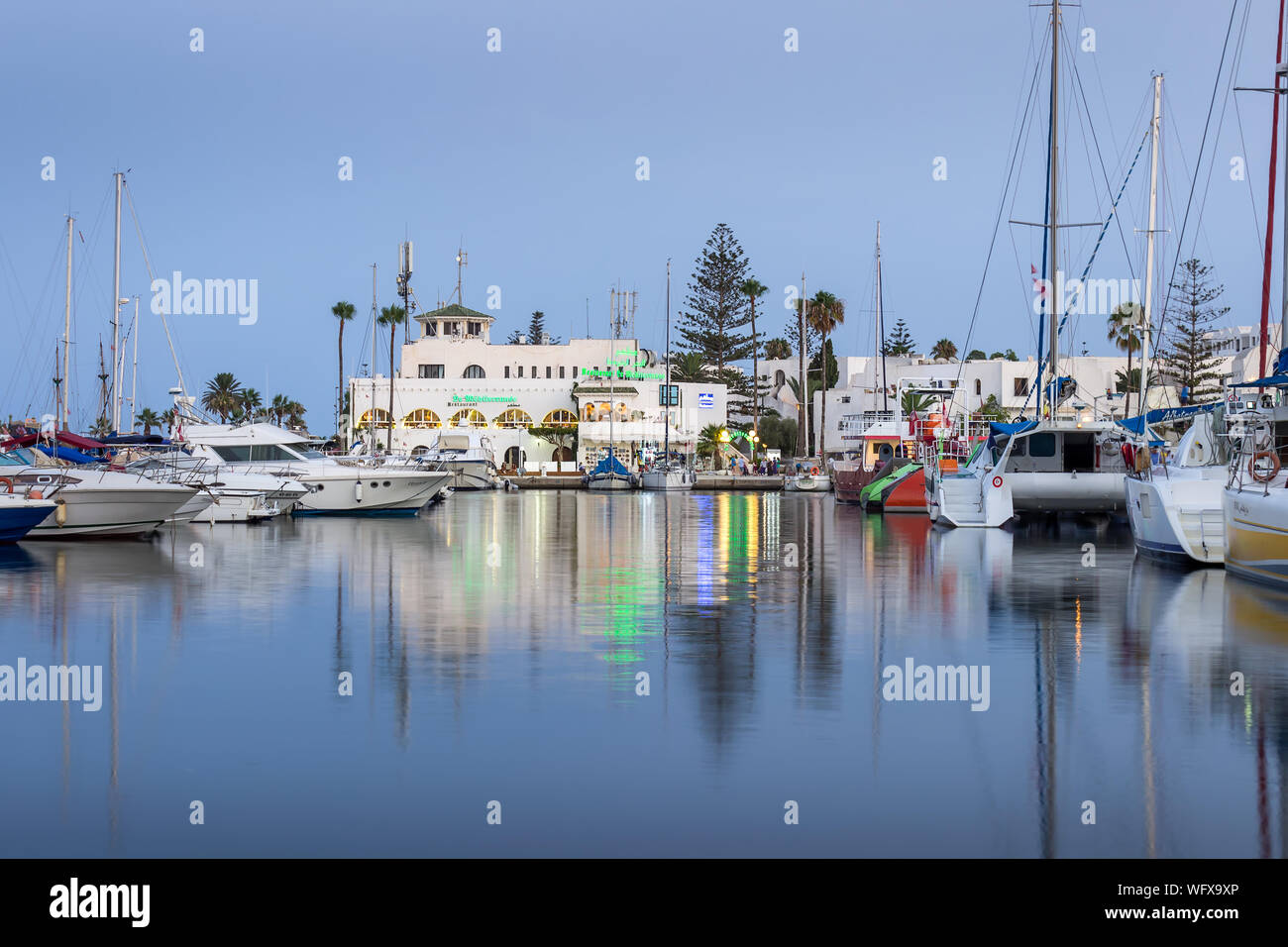 Heure bleue à Marina Port El Kantaoui, de beaux bateaux, yachts et bateaux stationnés dans la mer, restaurants et boutiques de cadeaux Banque D'Images