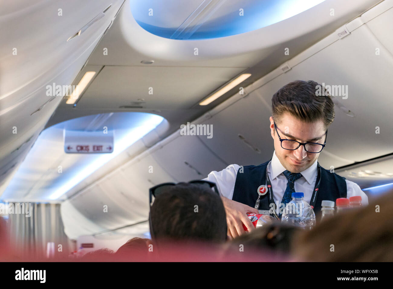 Istambul, Turquie - 27 juillet 2019 : un jeune homme qui sert des boissons à bord un passager à bord d'une cabine de classe économique. Banque D'Images