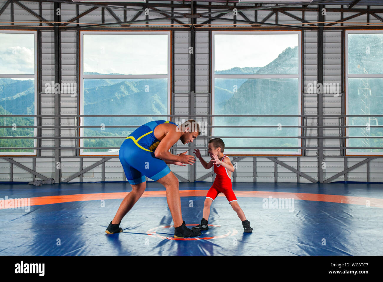 Un petit garçon dans un lutteur-sports se débat avec un homme adulte wrestler sur un tapis de lutte dans la salle de sport. Le concept de l'alimentation de l'enfant et martial Banque D'Images