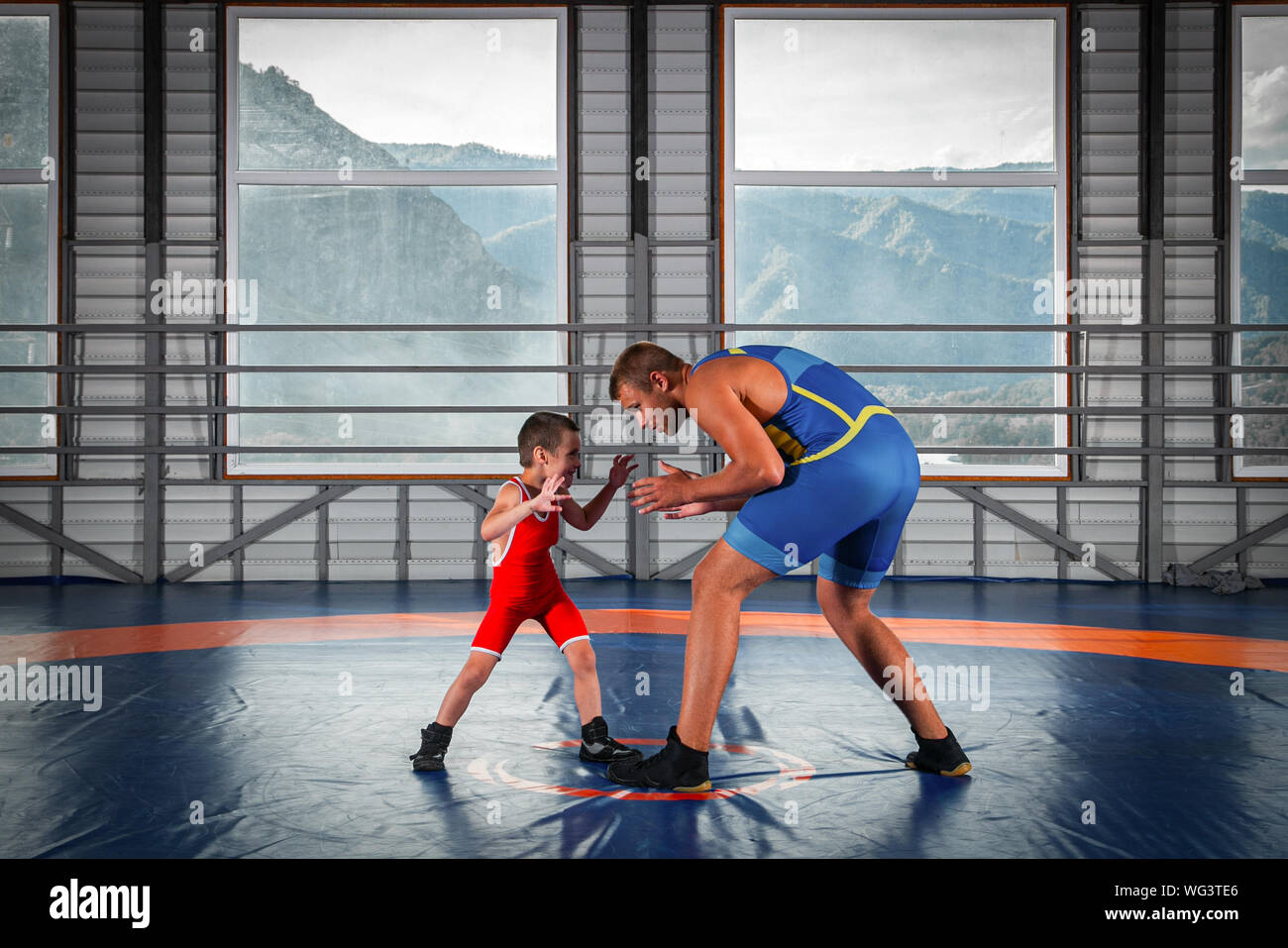 Un petit garçon dans un lutteur-sports se débat avec un homme adulte  wrestler sur un tapis de lutte dans la salle de sport. Le concept de  l'alimentation de l'enfant et martial Photo