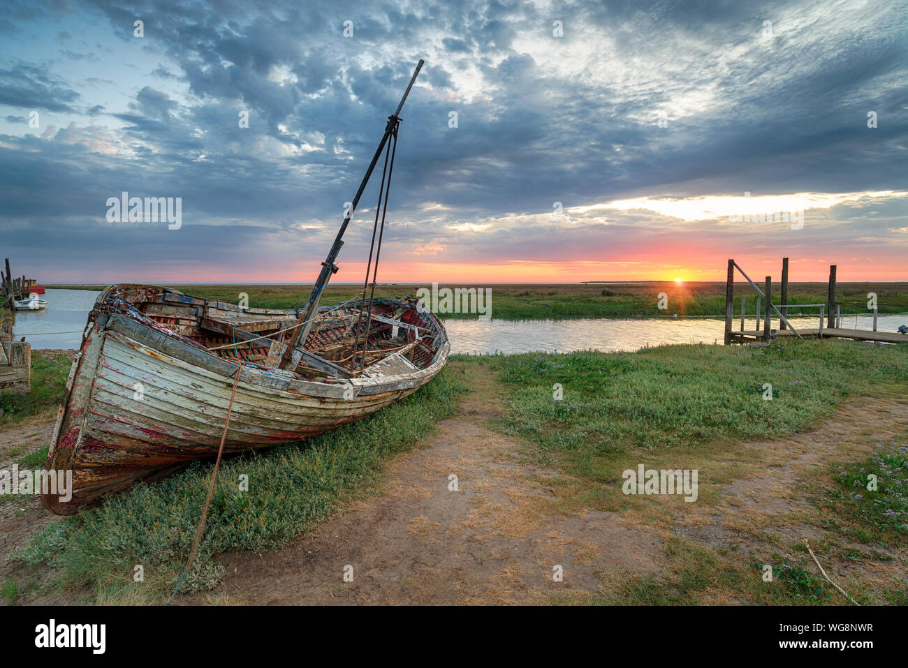 Lever de soleil sur spectaculaire d'un vieux bateau de pêche sur la berge à Thornham sur la côte nord de Norfolk Banque D'Images Lever de soleil sur spectaculaire d'un vieux bateau de pêche sur la berge à Thornham sur la côte nord de Norfolk Banque D'Images