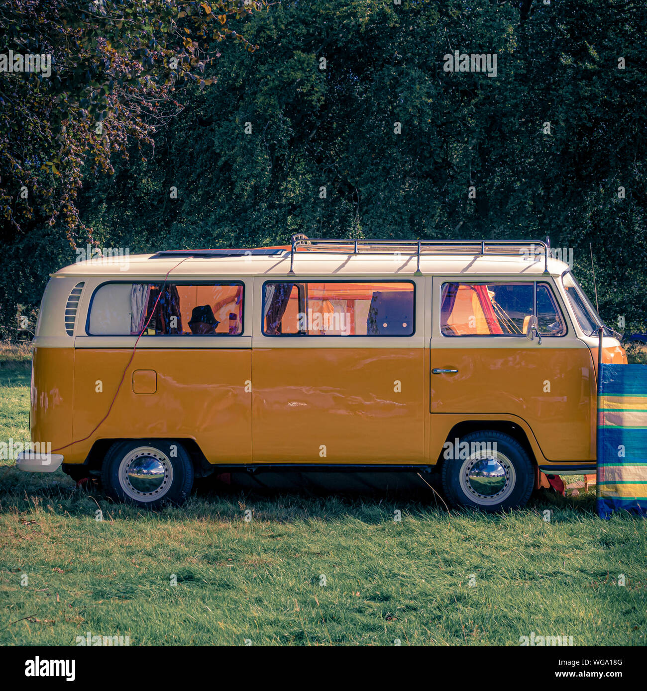 Camionnette Volkswagen traditionnelle orange et blanche sur le camping Banque D'Images