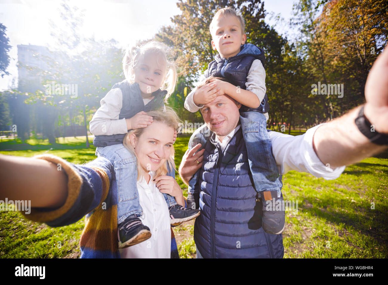 Charmante jeune couple taking self portrait photo selfies exerçant son fils et sa fille sur les épaules posant sourire heureux. Voir point tué père, mère Banque D'Images