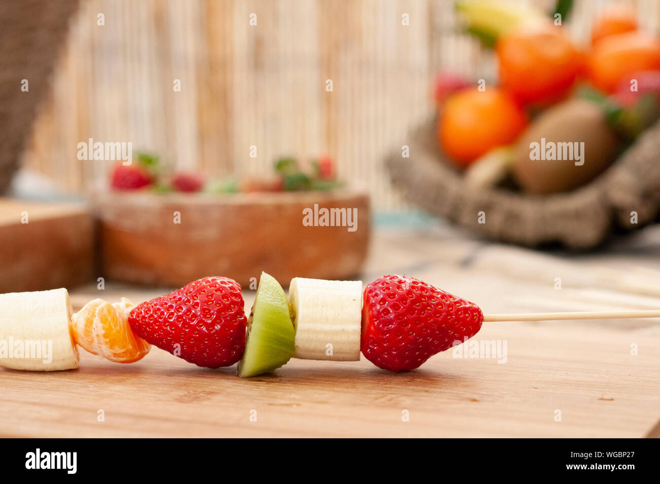 Banane-Fraise kiwi et clémentine placé sur une brochette en bois sur une planche en bois avec fond naturel très préparé pour la fondue au chocolat Banque D'Images