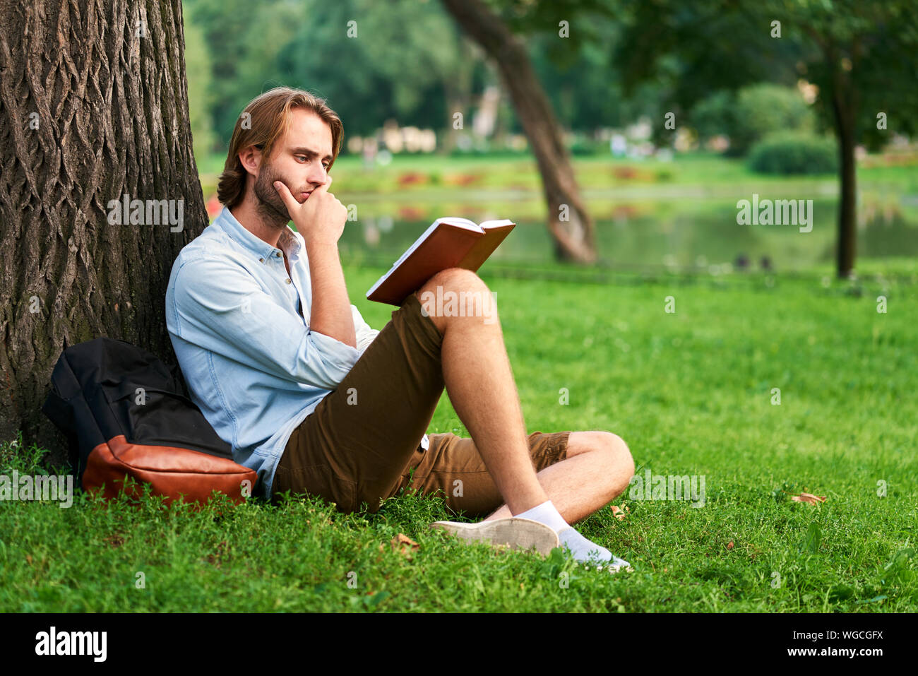 Étudiant sérieux dans la région de park of campus lire un livre. Banque D'Images
