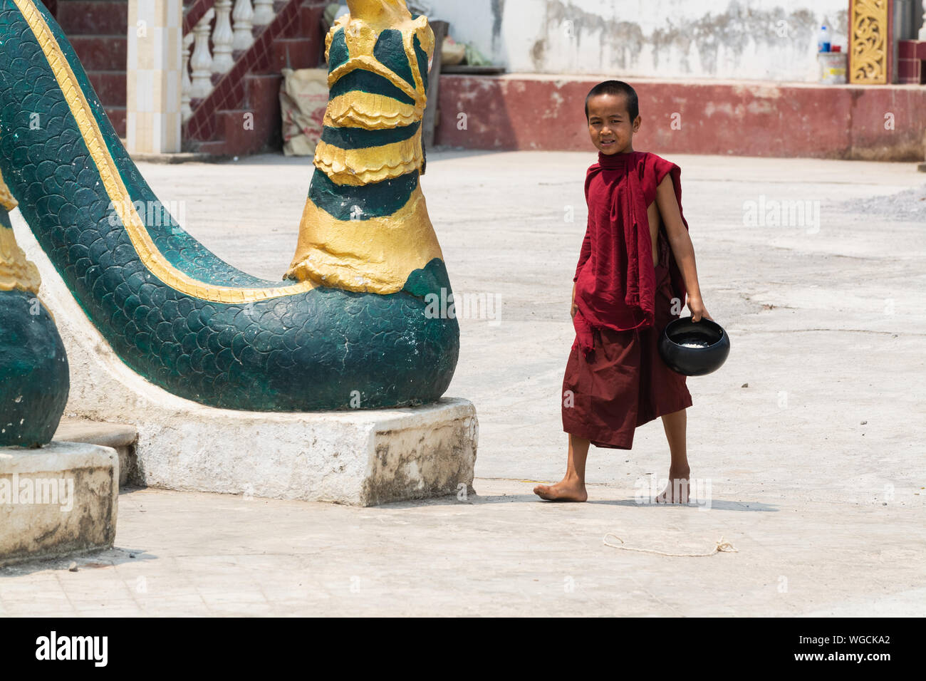 Inle, Myanmar - Avril 2019 : moine birman balade dans le monastère cour avec bol de riz dans ses mains Banque D'Images