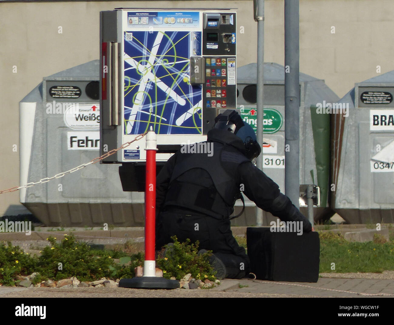 Un spécialiste de l'Office de la sûreté de l'État est chargé de désamorcer un engin explosif dans un distributeur automatique de cigarettes. Après la découverte de deux bombes tuyaux dans un distributeur automatique de cigarettes, les maisons voisines ont été évacuées et une route était fermée. Banque D'Images