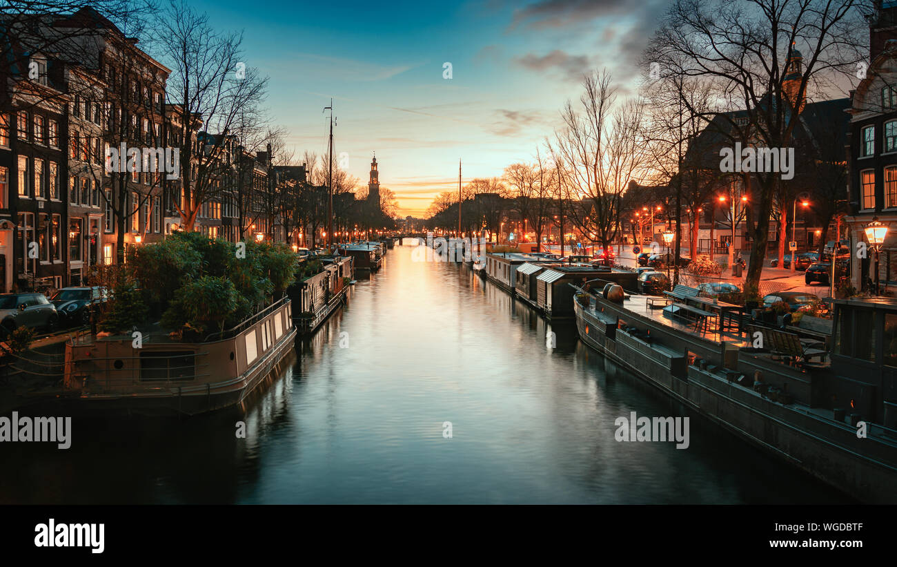 Péniches sur le Prinsengracht dans le vieux centre d'Amsterdam aux Pays-Bas avec la flèche de la Westertoren en arrière-plan pendant le coucher du soleil Banque D'Images