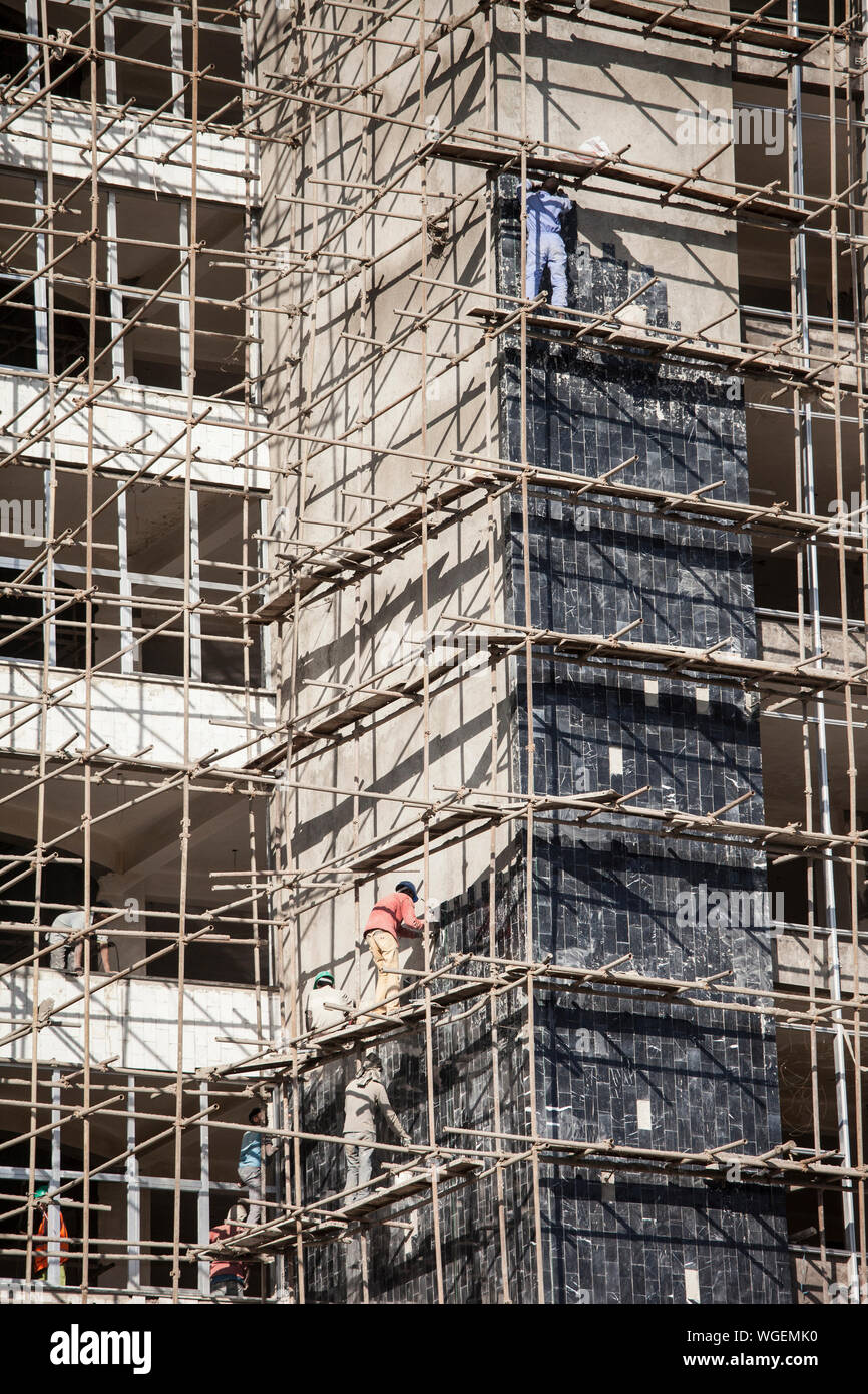 Mettre les ouvriers du bâtiment façade tuiles sans équipement de sécurité en Ethiopie Banque D'Images