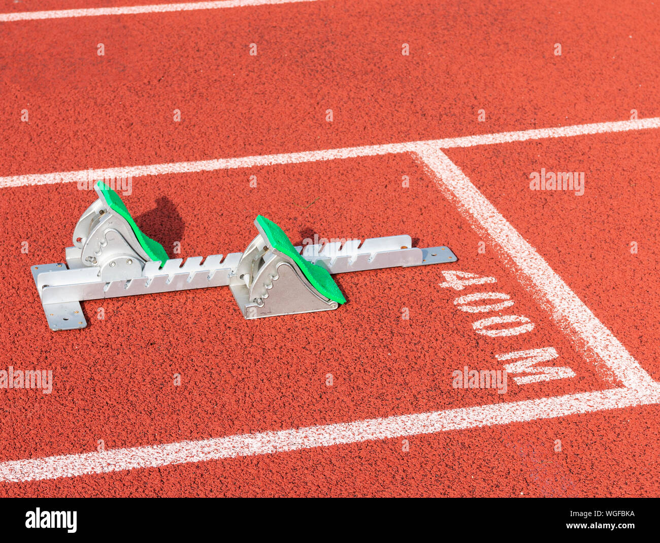 Un ensemble de l'athlétisme sprinters starting-blocks avec tampons vert, est mis en place à la ligne de départ dans les ruelles de la 400 mètres. Banque D'Images