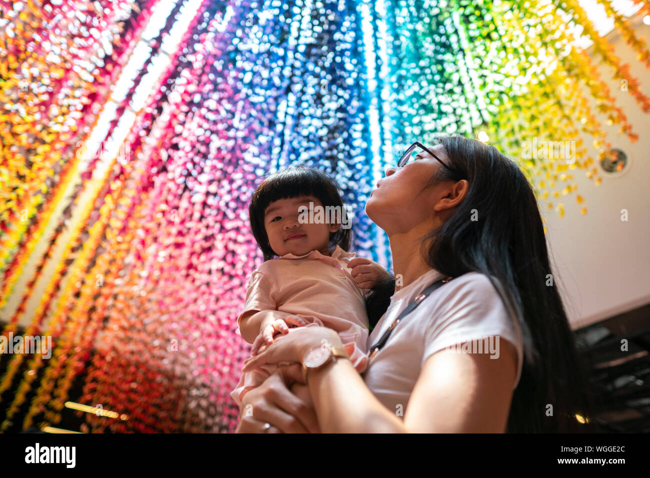 Young Asian mother holding her girl donnant sur le Rainbow Paper Cranes. Banque D'Images