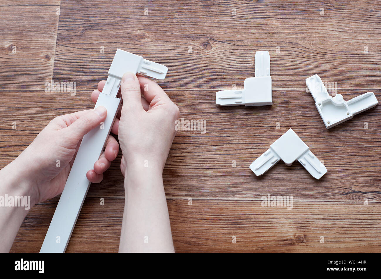 Accessoires pour fenêtres en plastique. Zone plastique de moustiquaires et de profil d'aluminium dans les mains. Sur un fond en bois brun. Banque D'Images