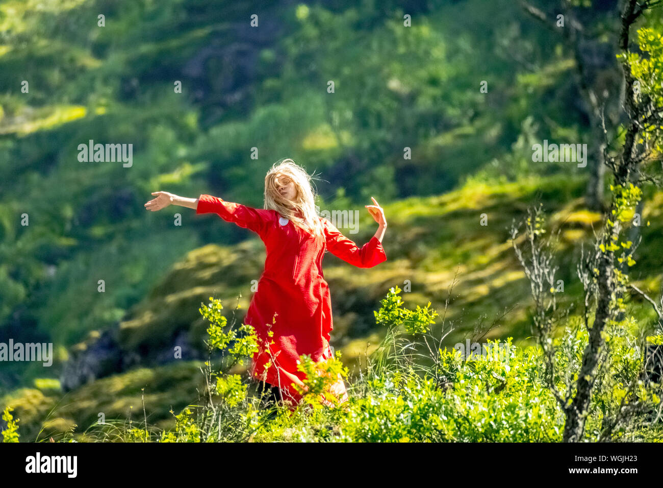 Femme habillée en rouge est une fée, Huldra, saga figure, cascade Kjosfossen, chute près de Fureberget, danseuse en robe rouge, murs de pierre, Flåm, Sogn og Fjo Banque D'Images