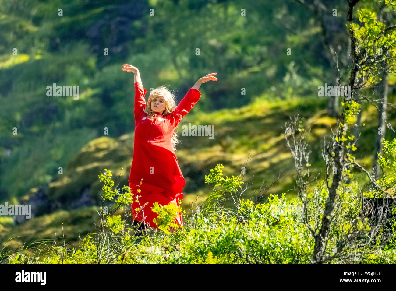 Femme habillée en rouge est une fée, Huldra, saga figure, cascade Kjosfossen, chute près de Fureberget, danseuse en robe rouge, murs de pierre, Flåm, Sogn og Fjo Banque D'Images