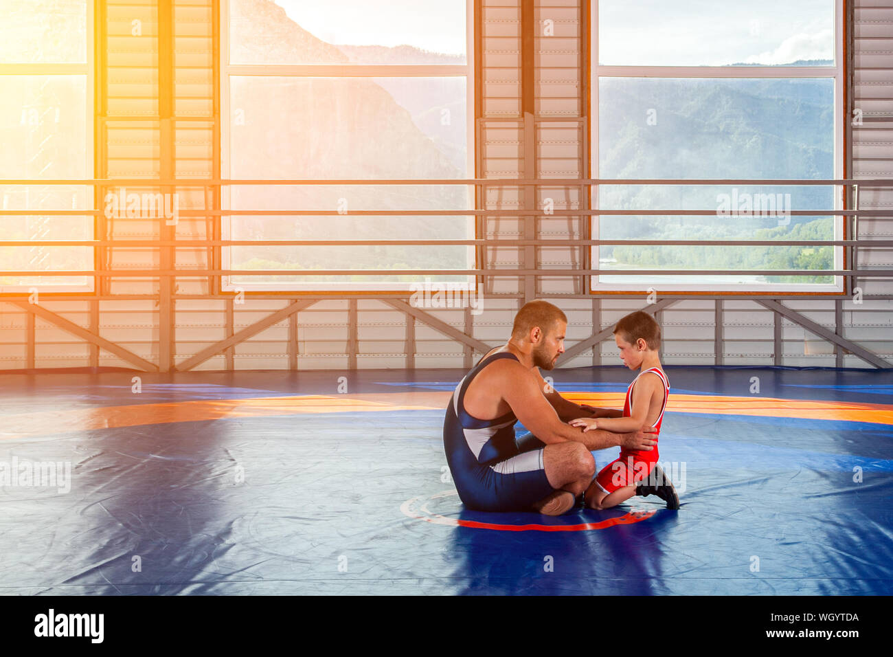 Un homme adulte wrestler coach enseigne les bases de la lutte et met en place un petit garçon à la concurrence. Le concept de l'alimentation de l'enfant et la formation d'arts martiaux Banque D'Images