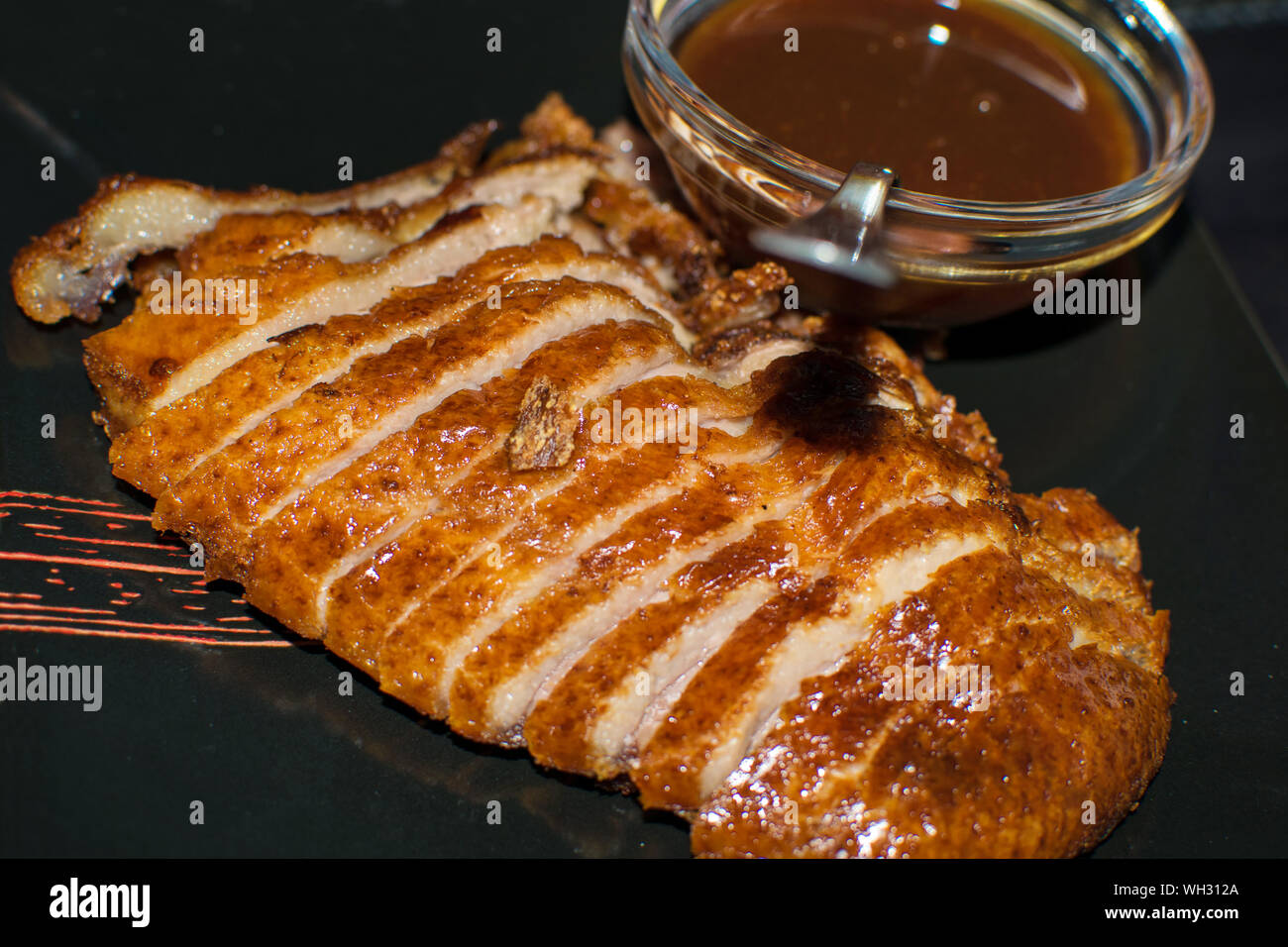 Photo en gros plan de le canard rôti servi avec sauce à l'orange sur fond noir plat. Cuisine chinoise dans l'Espagne, 2019. Canard Orange plat gastronomique. Banque D'Images