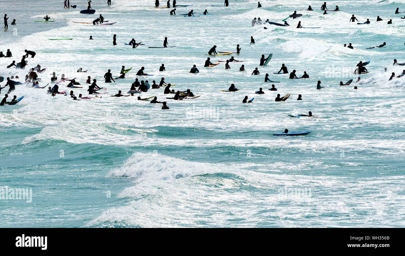 Les vacanciers s'amuser dans la mer vu en silhouette à Newquay dans Fistral à Cornwall. Banque D'Images