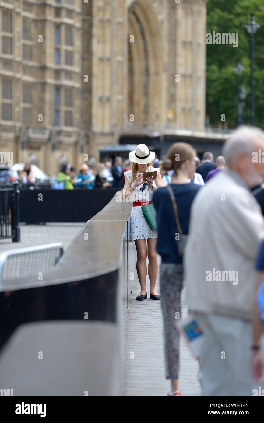 Londres, Angleterre, Royaume-Uni. Woman son téléphone à l'extérieur du Parlement Banque D'Images