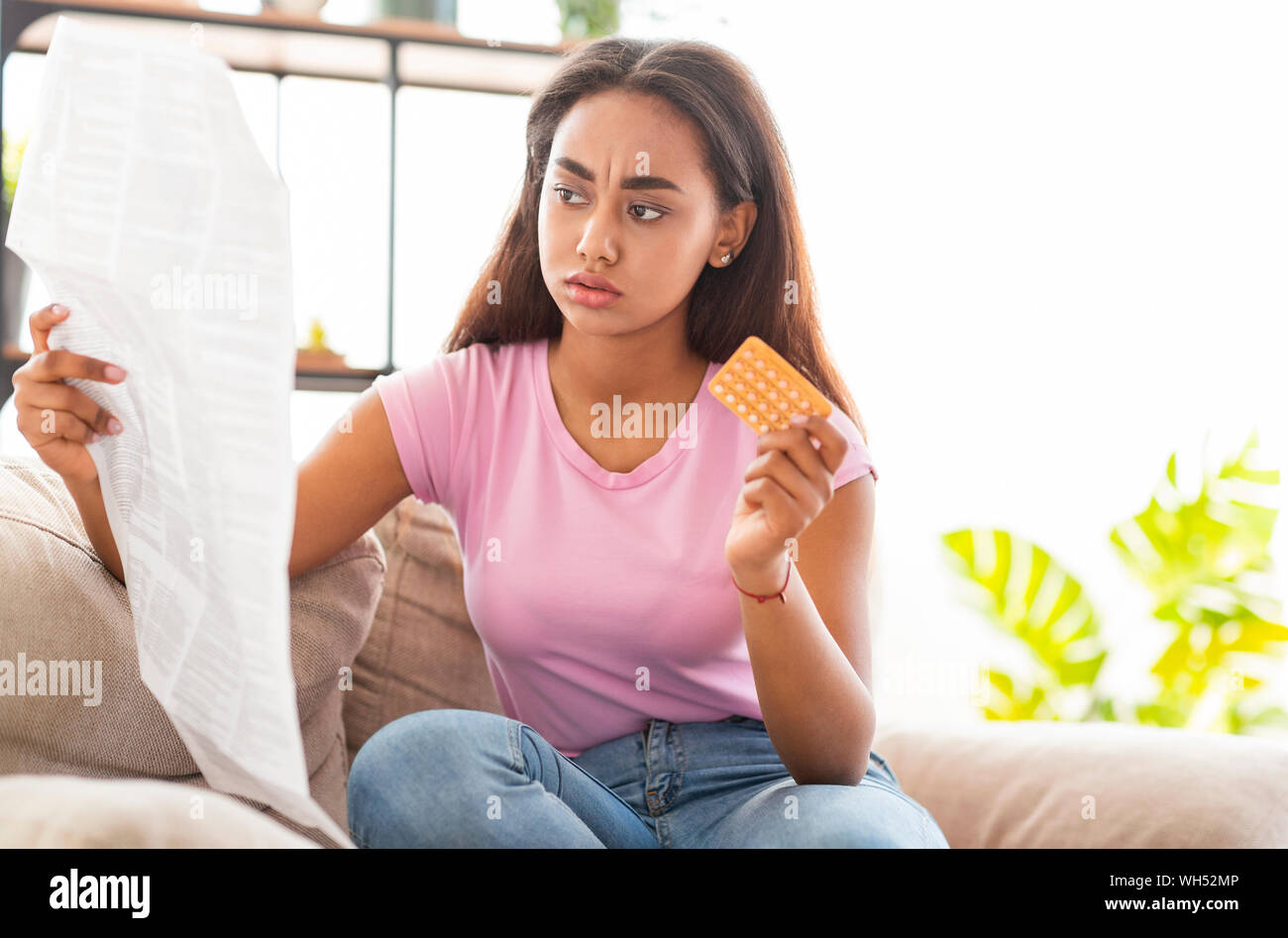 Choqué african american girl reading leaflet avant de prendre des pilules contraceptives Banque D'Images