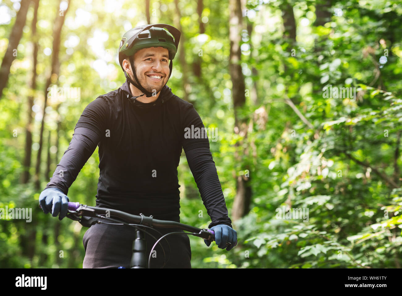 Homme joyeux cycliste à vélo dans la forêt de montagne Banque D'Images