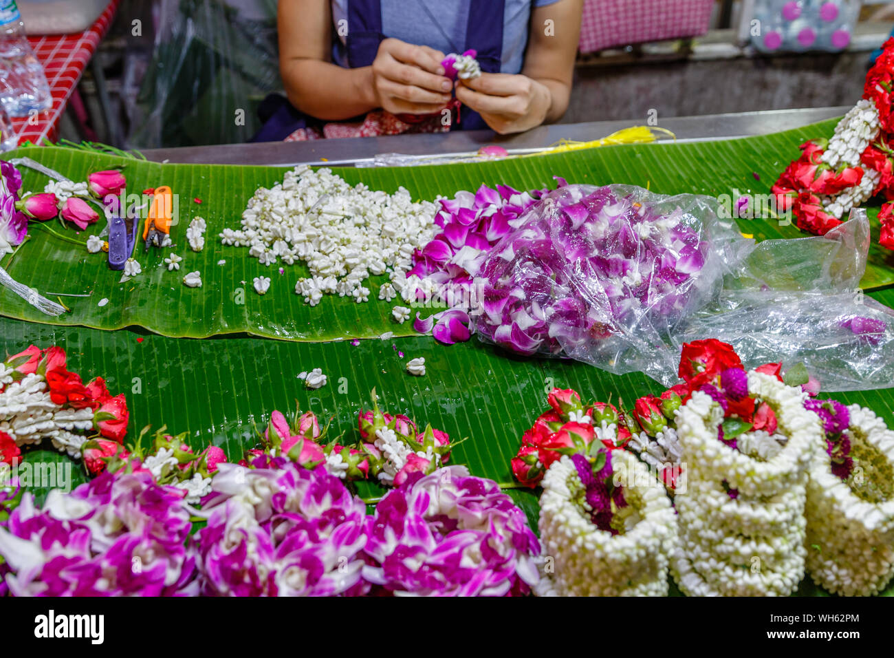 Woman making Phuang malai, fleur traditionnelle thaïlandaise garland offre avec jasmin et orchidées à Pak Khlong Talat, marché aux fleurs de Bangkok. La Thaïlande. Banque D'Images