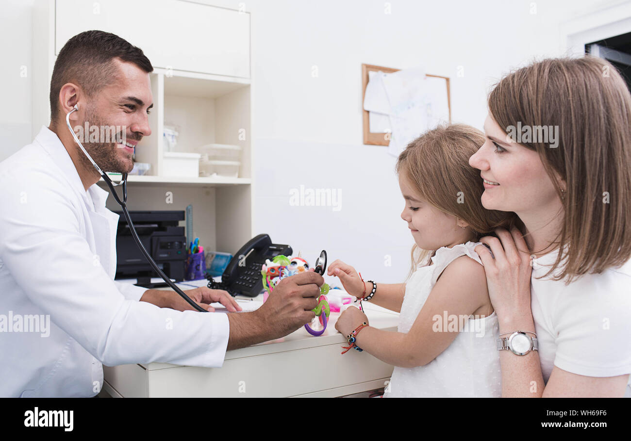 Médecin pédiatrie positive tout en travaillant avec un enfant. mère avec un enfant examiné par un pédiatre Banque D'Images