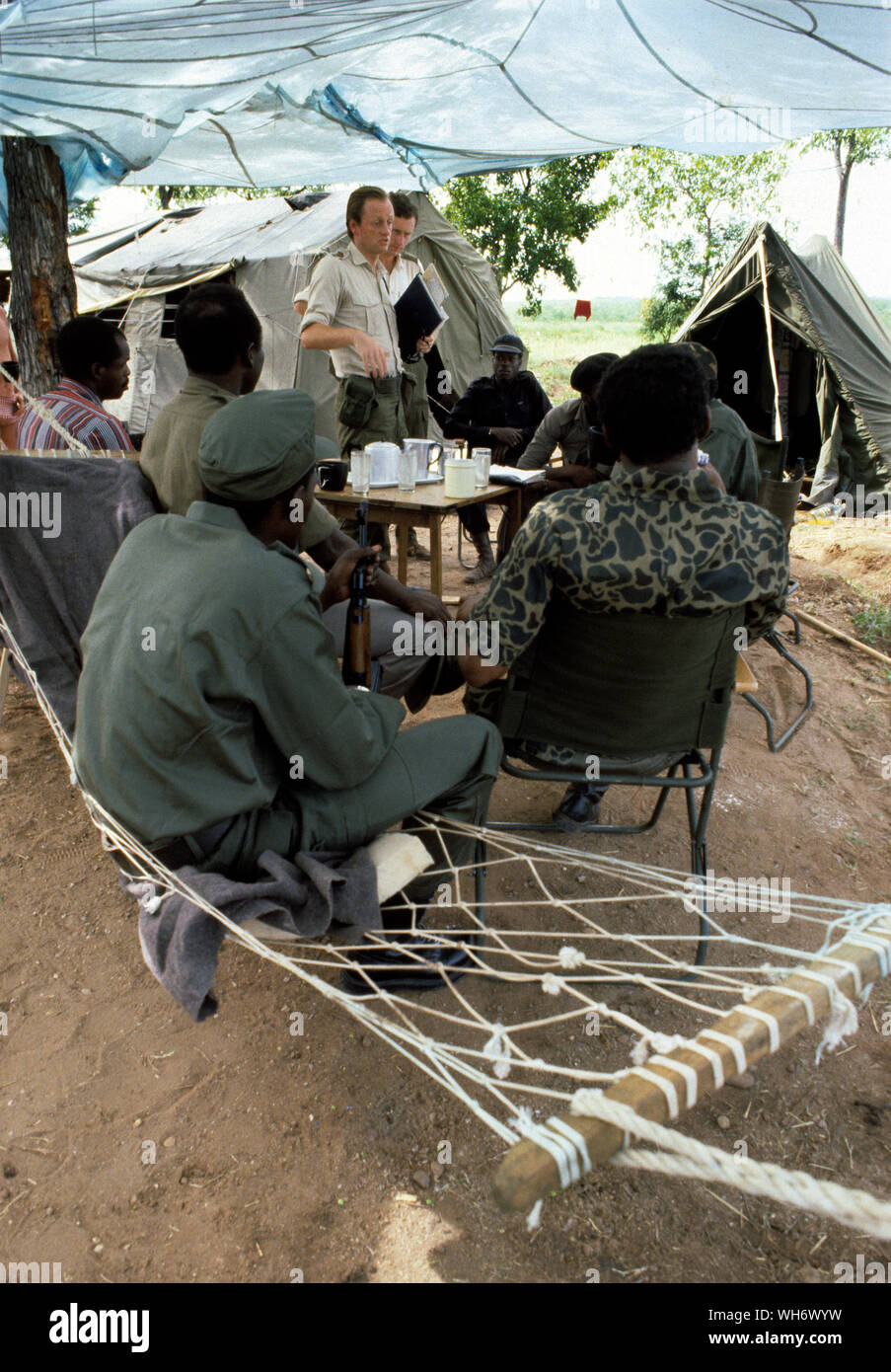 Lt colonel Andrew Parker Bowles, centre avec dossier bleu, au Camp Alpha, Rhodesia-Zimbabwe 1980. Il est vu la supervision des troupes du Front Patriotique qui nous arrivent de la brousse dans la holding de l'Armée britannique des camps dans la vallée du Zambèze dans le cadre du processus de paix de Lancaster House après la fin de la guerre civile de la Rhodésie. Il était officier de liaison à lord Soames, lorsqu'il était gouverneur de la Rhodésie au cours de la période de transition vers l'état de règle majoritaire du Zimbabwe en 1979-1980. Il a été un personnel qualifié (SQ), et est devenu un lieutenant-colonel le 30 juin 1980.AK47AK47, il a reçu le Queen's Commendation fo Banque D'Images