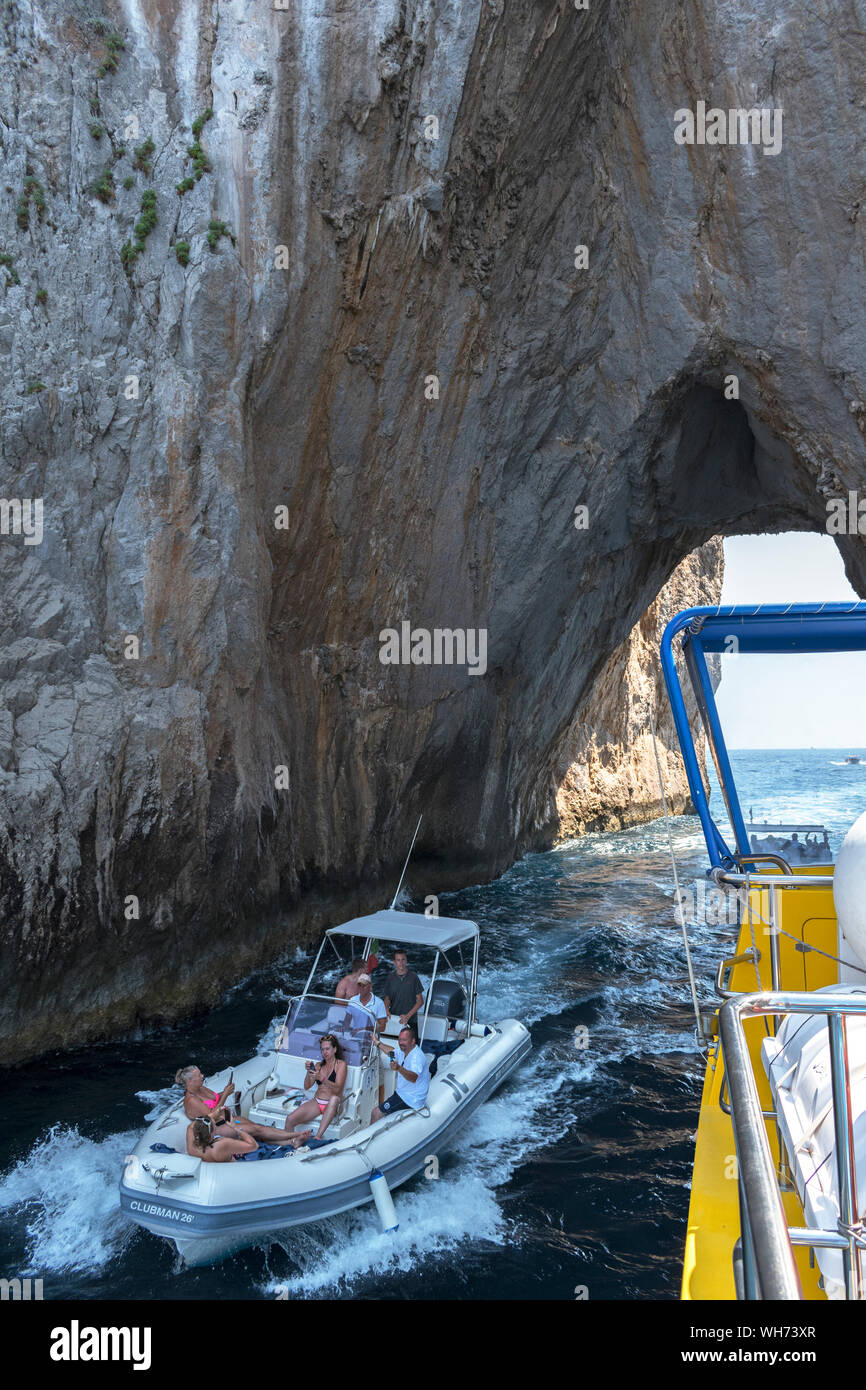 Les touristes sur un bateau traversant la voûte dans les faraglioni hors de l'île de Capri, Italie. Banque D'Images