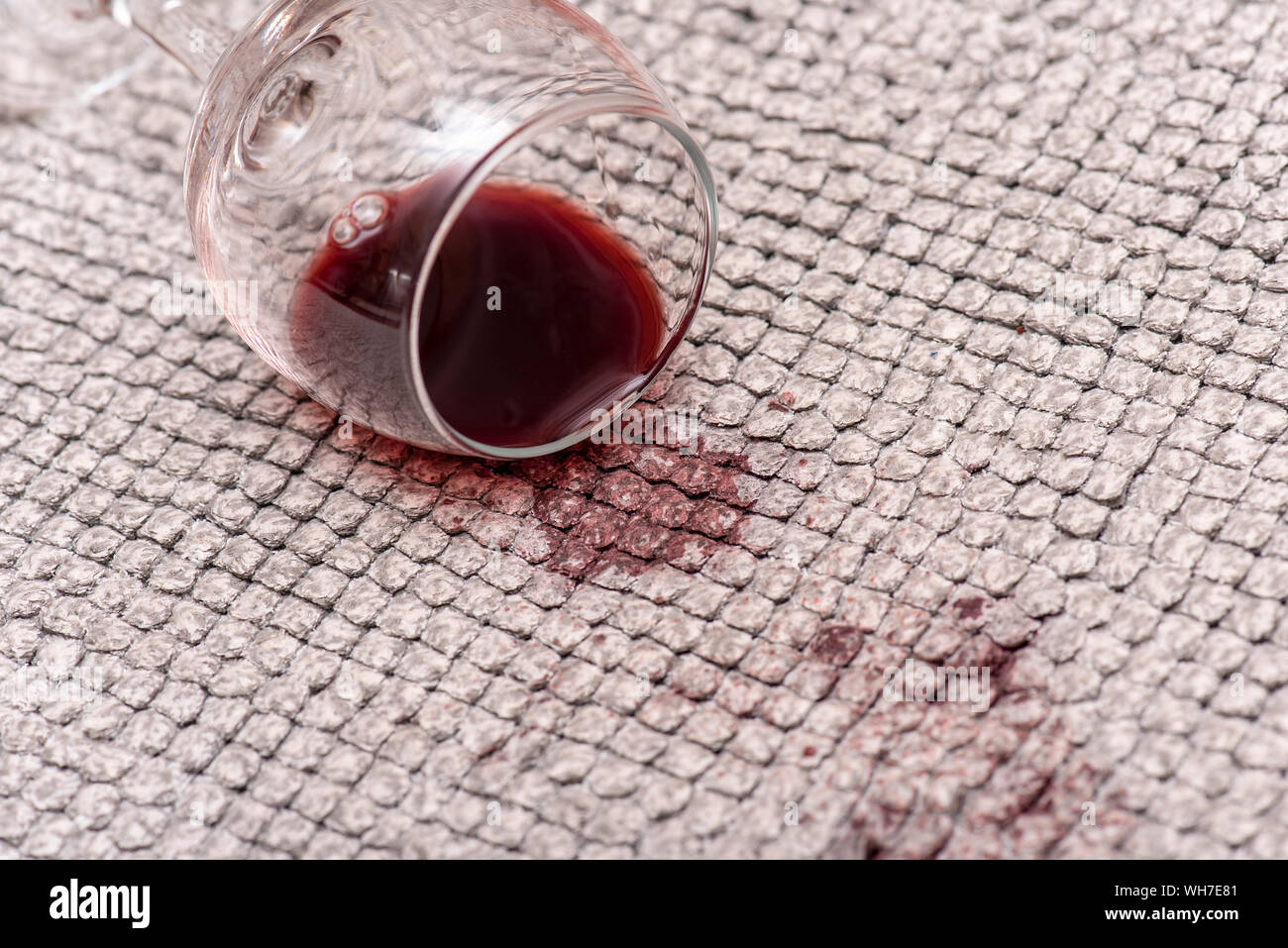 Verre à vin rouge sur le sol, le vin rouge renversé sur un tapis, les taches et les taches par boisson, close-up Banque D'Images