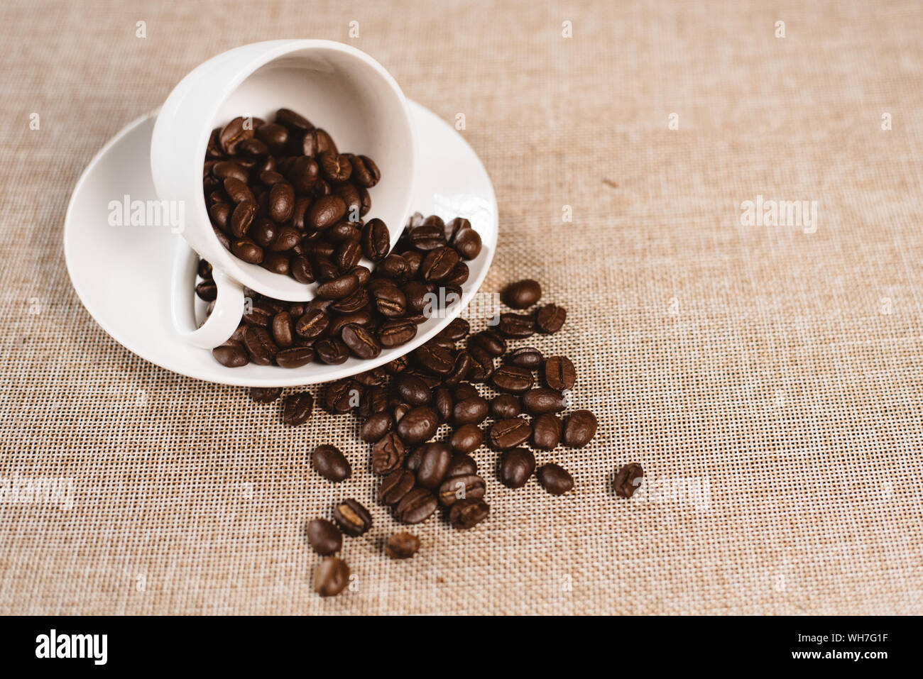 Sur un débordement de grains de café tasse blanche sur un sac de jute. concept de boisson préférée et l'agriculture Banque D'Images