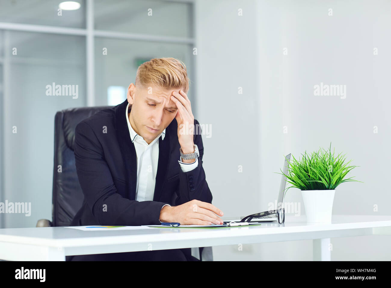 Malheureux,maux de tête,homme malade assis à une table dans le bureau. Banque D'Images