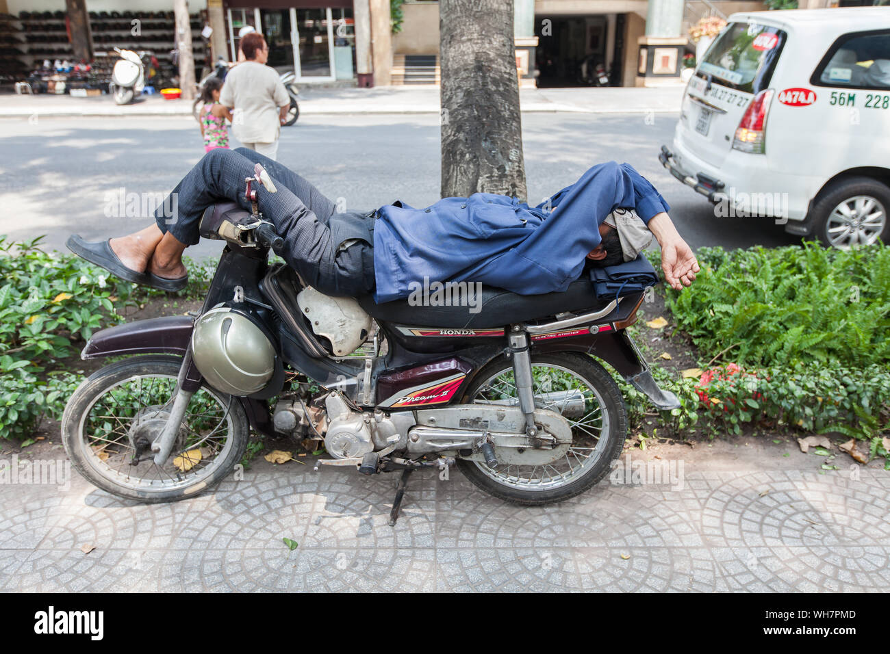 Courant dans la ville pour voir Xe Om/ pilote moto prendre une sieste sur leur moto taxi quand il n'y a pas de client, Ho Chi Minh City, Vietnam. Banque D'Images