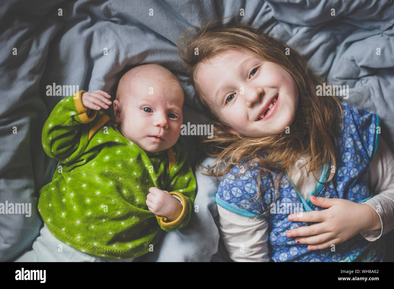 Portrait of smiling little girl lying on lit à côté de petite fille, vue de dessus Banque D'Images