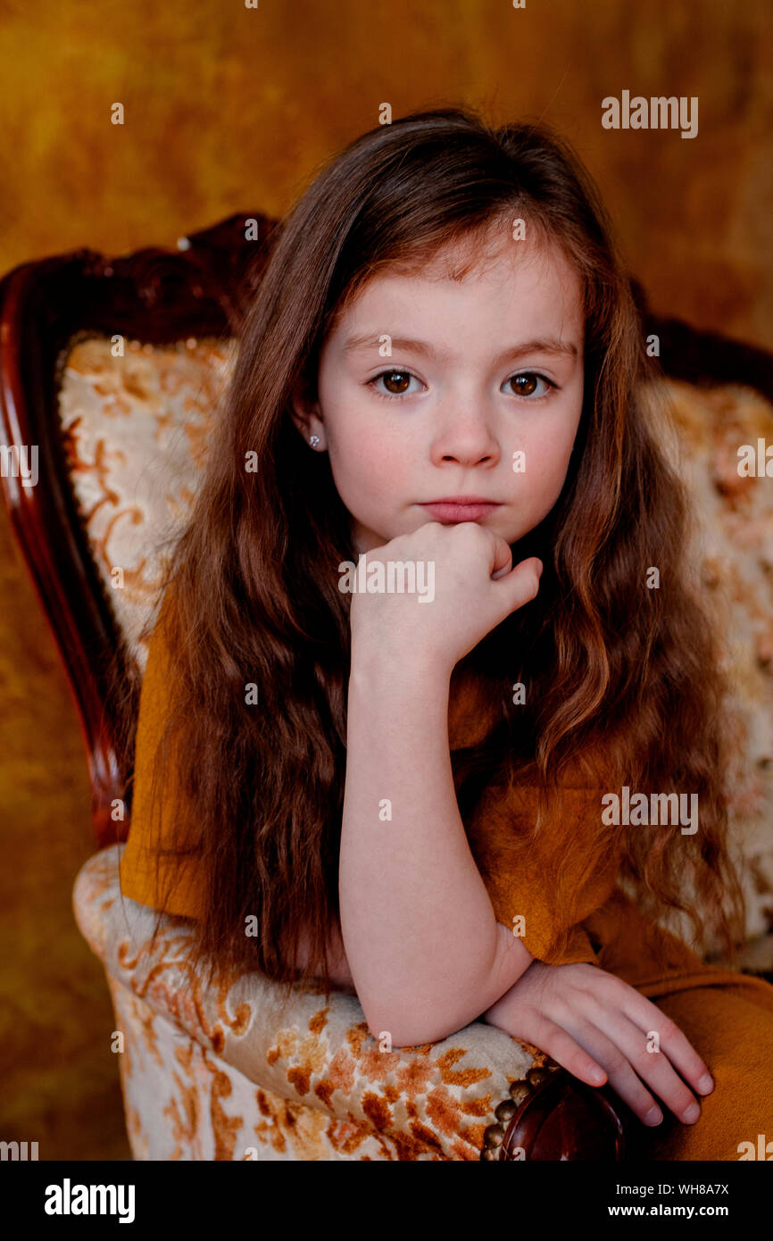 Portrait de petite fille assise sur la chaise de salon Banque D'Images