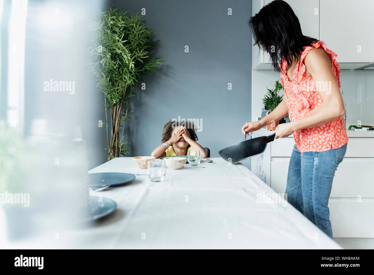 Mère servant repas pour fille assis à table à manger Banque D'Images