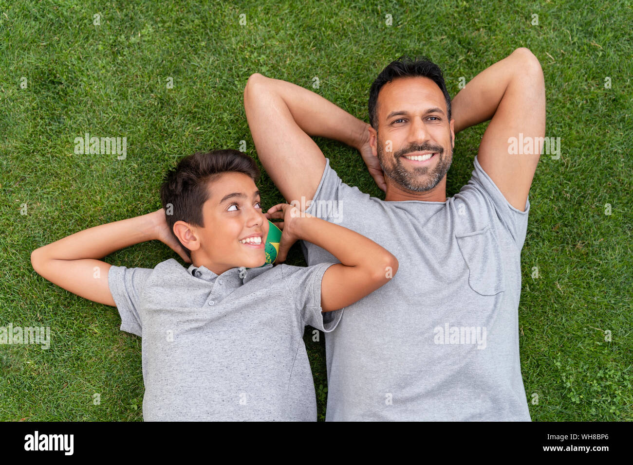 Heureux père et fils ensemble lying in grass Banque D'Images
