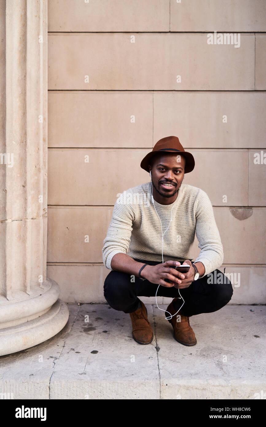 Mid adult man using smartphone et écouter de la musique Banque D'Images