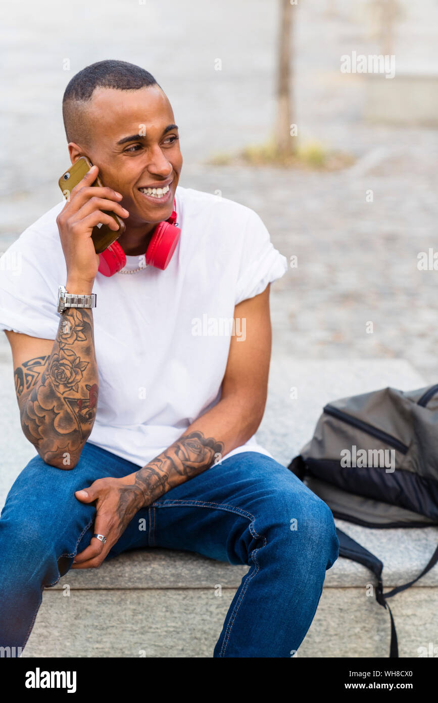 Portrait de jeune homme tatoué sur le téléphone assis sur un banc Banque D'Images