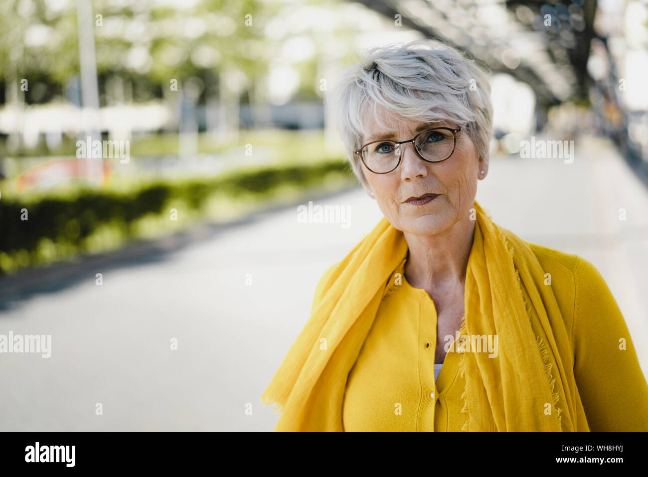 Portrait de femme mature aux cheveux gris portant des lunettes et vêtements  jaune Photo Stock - Alamy