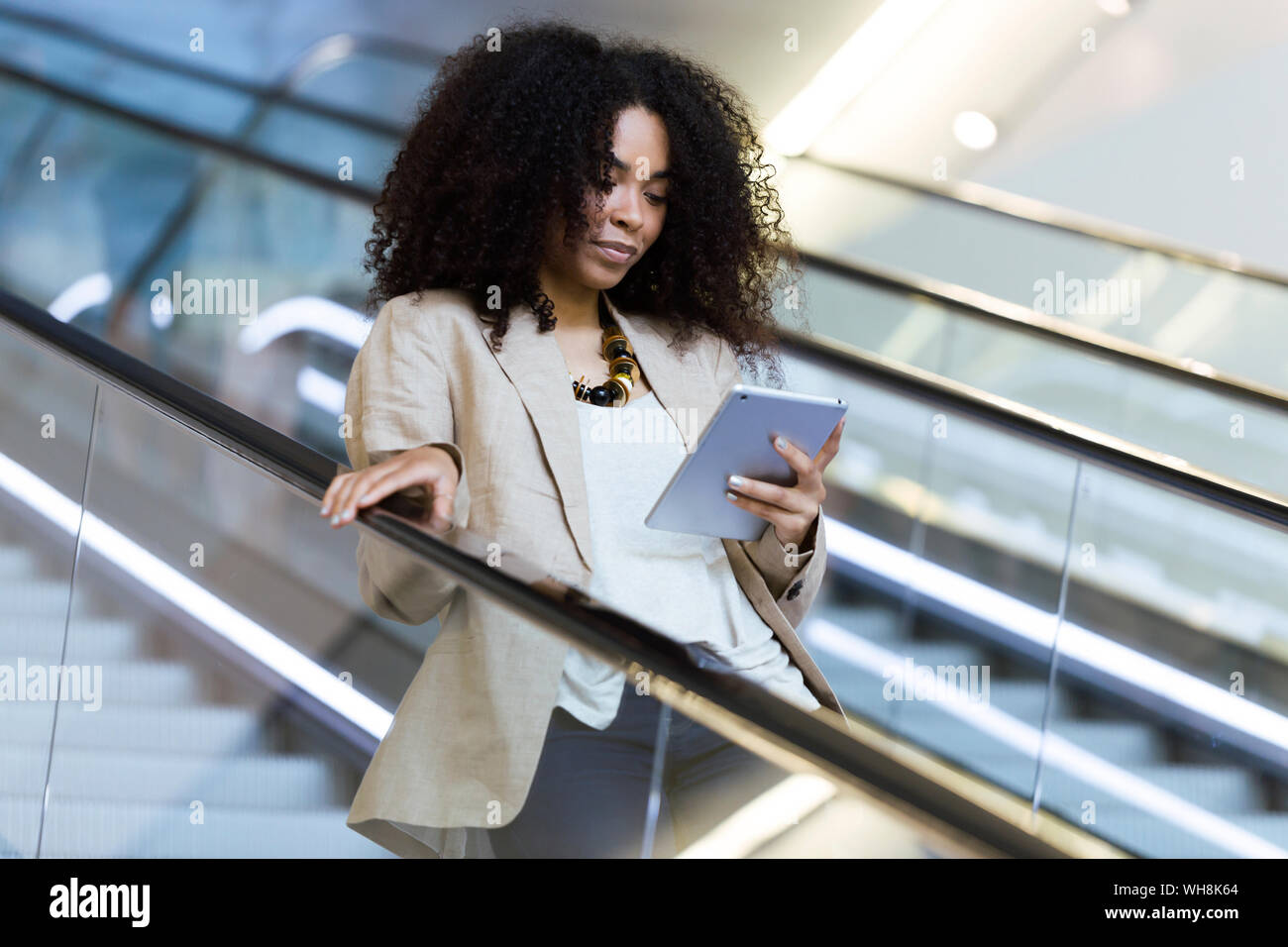 Young businesswoman using a tablet sur un escalator Banque D'Images