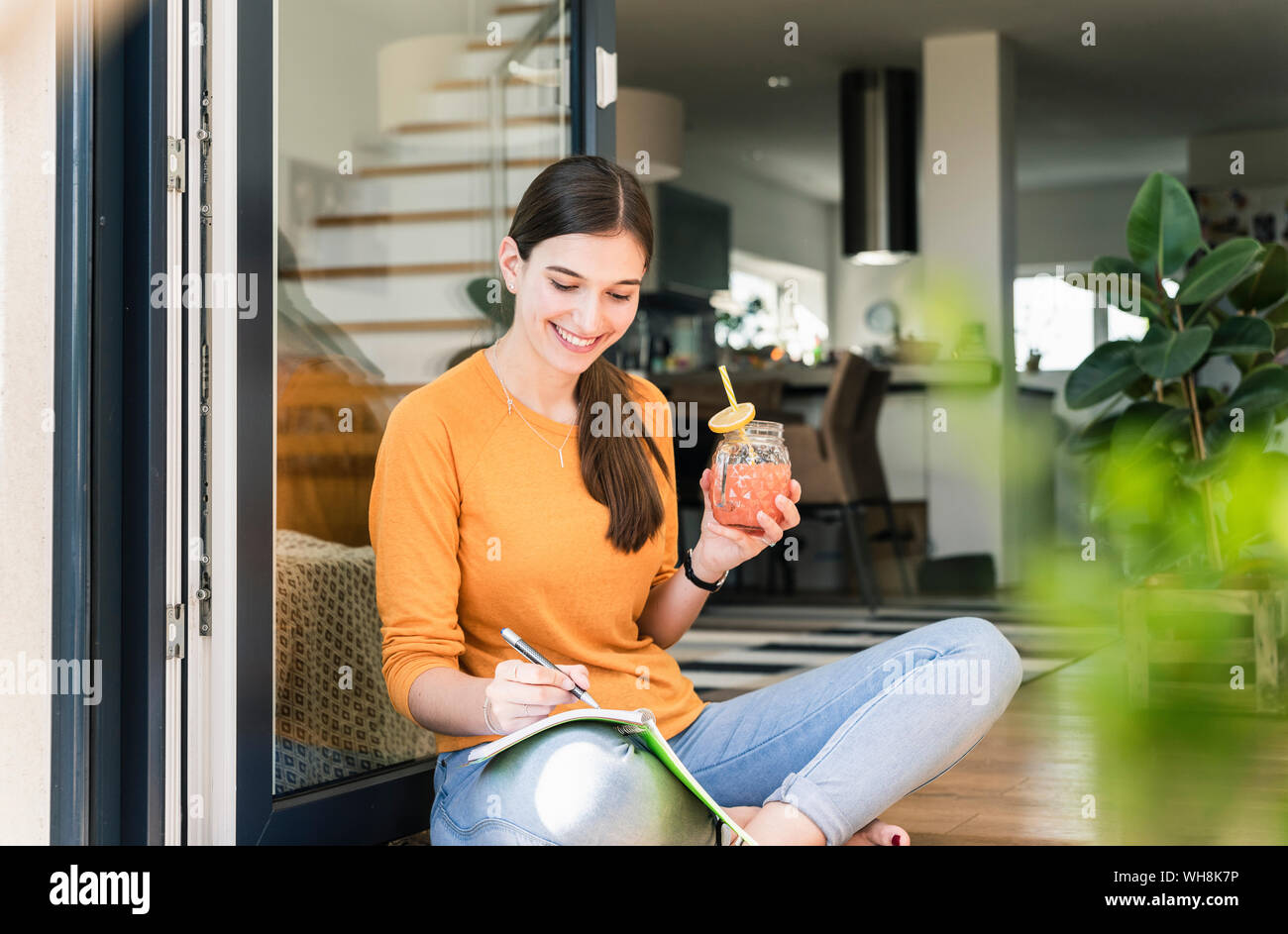 Jeune femme assise avec boisson saine et pc portable à la porte de terrasse Banque D'Images