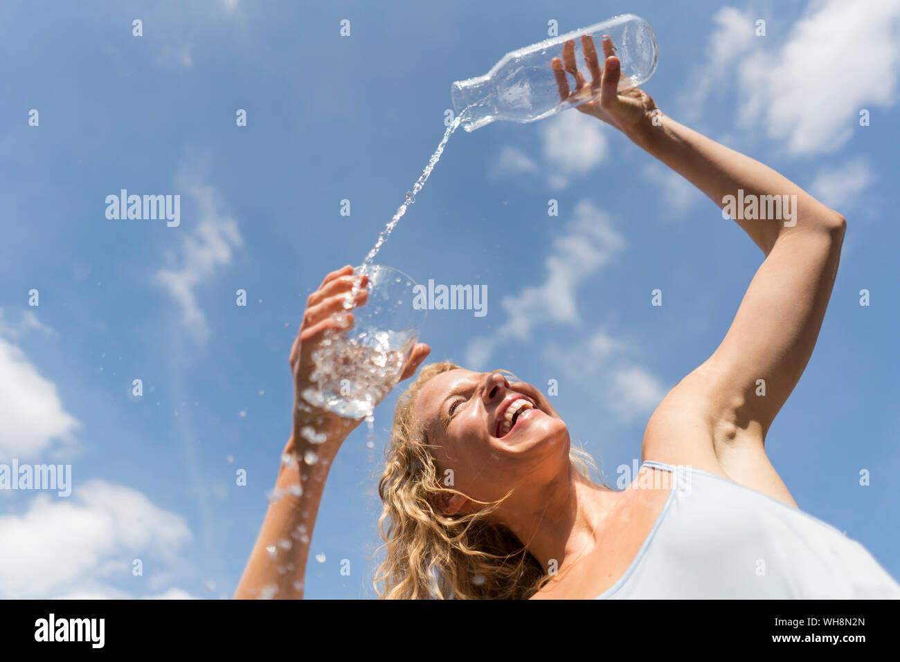 Femme versant de l'eau dans un verre en plein air, low angle view Banque D'Images